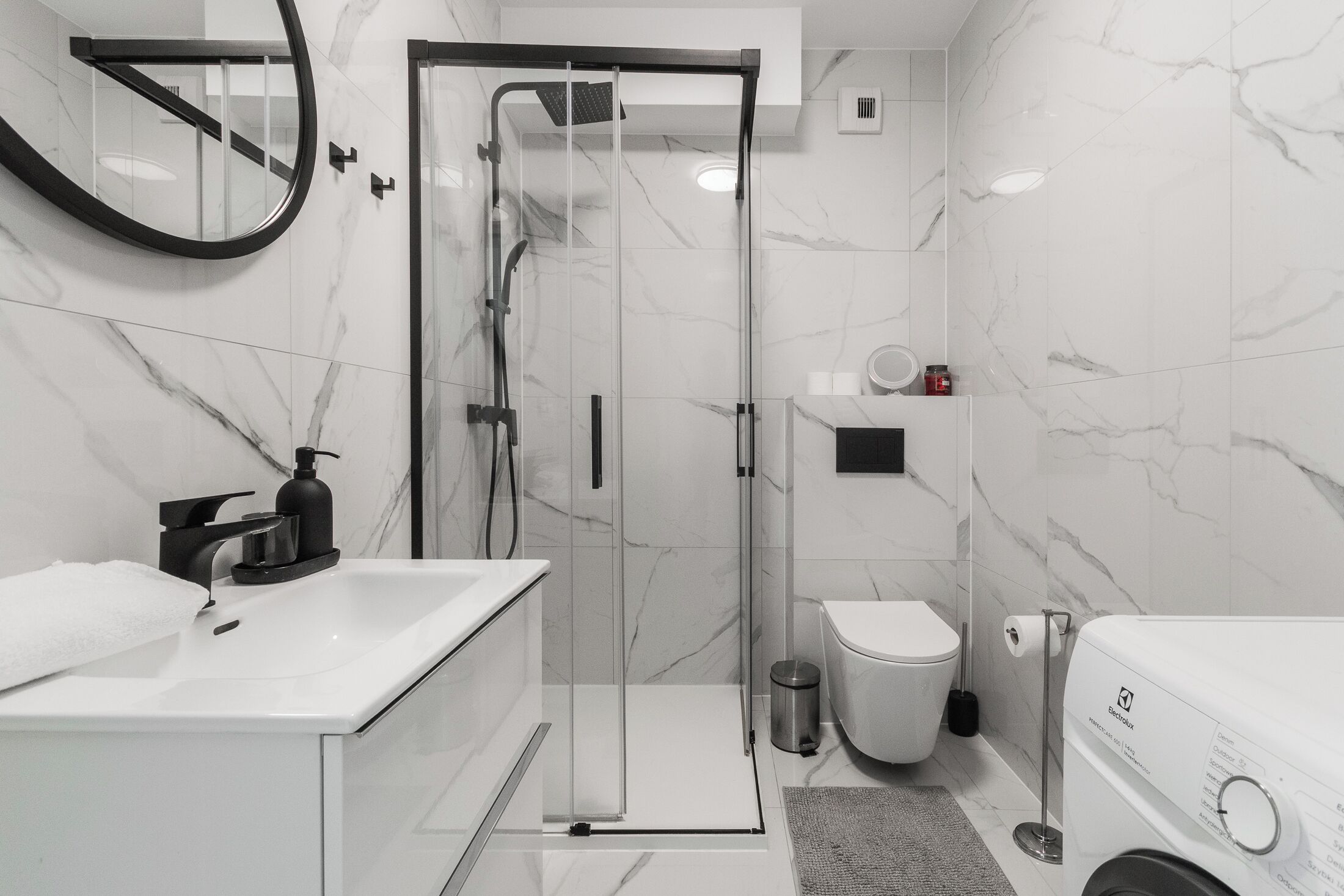 Ein modernes Badezimmer mit einer Glaskabine zur Dusche, einem weißen Waschbecken, einer Toilette und einem Bidet.