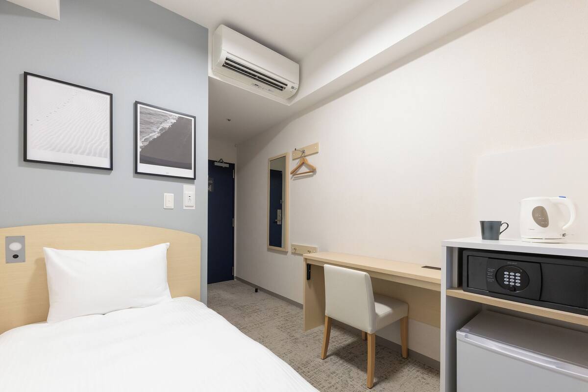 Een hotelkamer met een bed, een bureau, een stoel, een magnetron en een koffiezetapparaat.