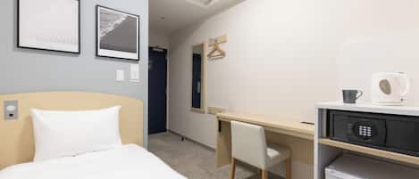 Habitación de hotel con cama, escritorio, silla, microondas y cafetera.