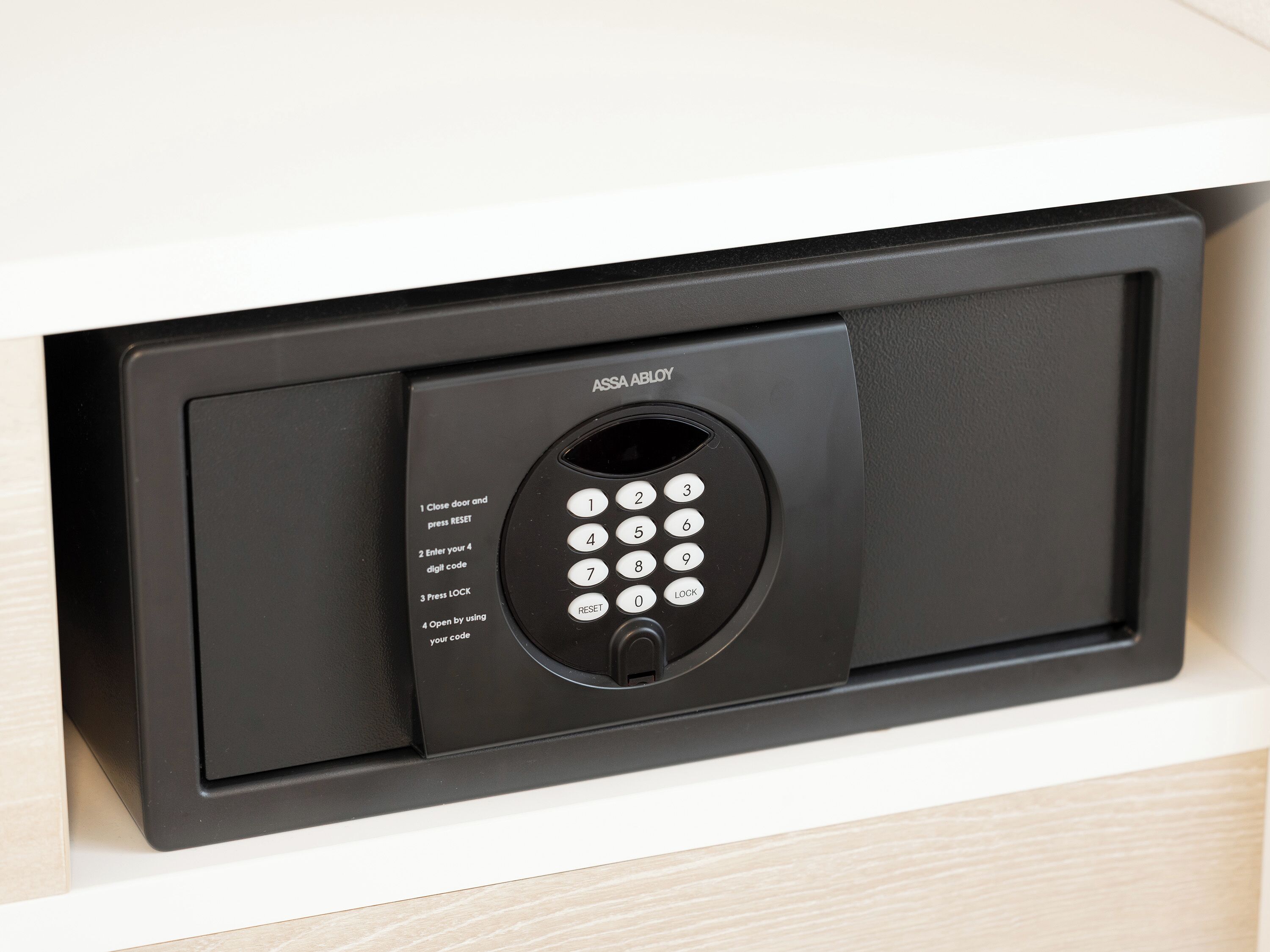 Cerradura de puerta ASSA ABLOY negra con teclado y instrucciones de funcionamiento.