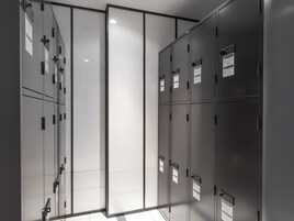 A modern, minimalist locker room with metallic lockers and a glass partition.