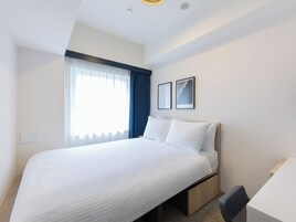 Une chambre d’hôtel avec un grand lit, un bureau et une fenêtre avec des rideaux.