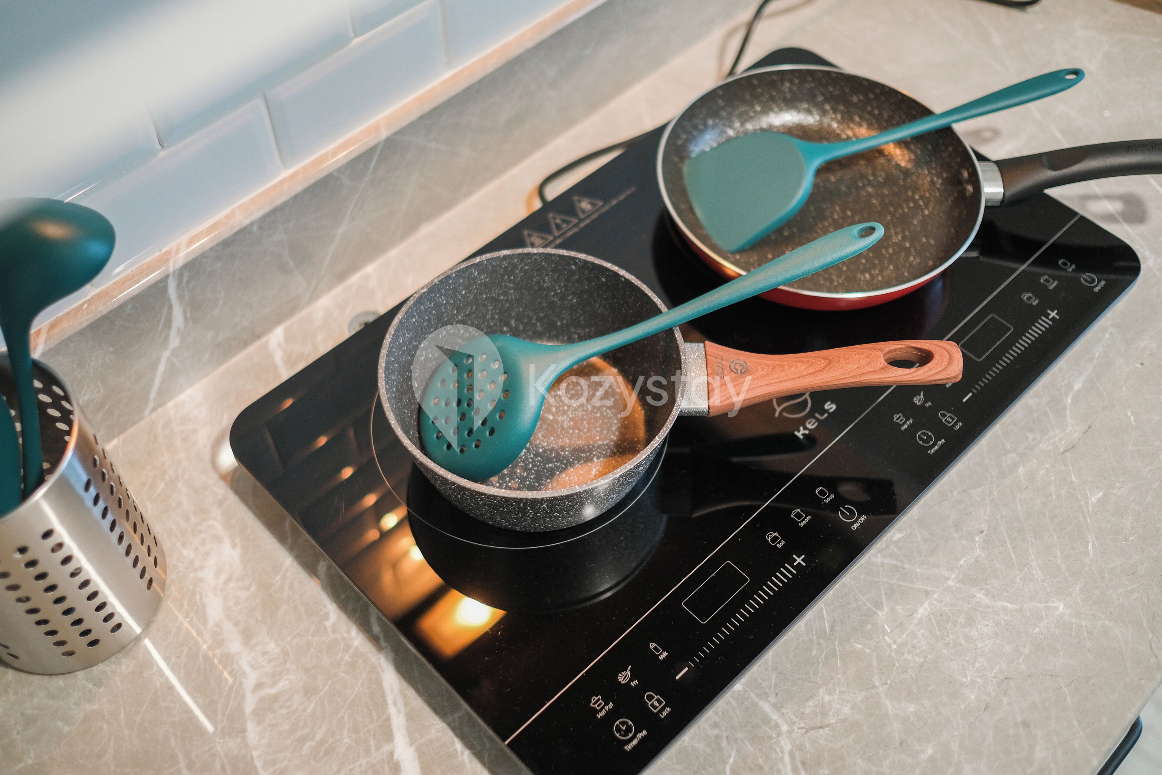 Une cuisine équipée d’une plaque de cuisson, de deux casseroles et d’une râpe.