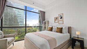 A modern hotel room with a large bed, a chair, a nightstand, and a city view. - Marmo by Kozystay - Kuningan (Jakarta)