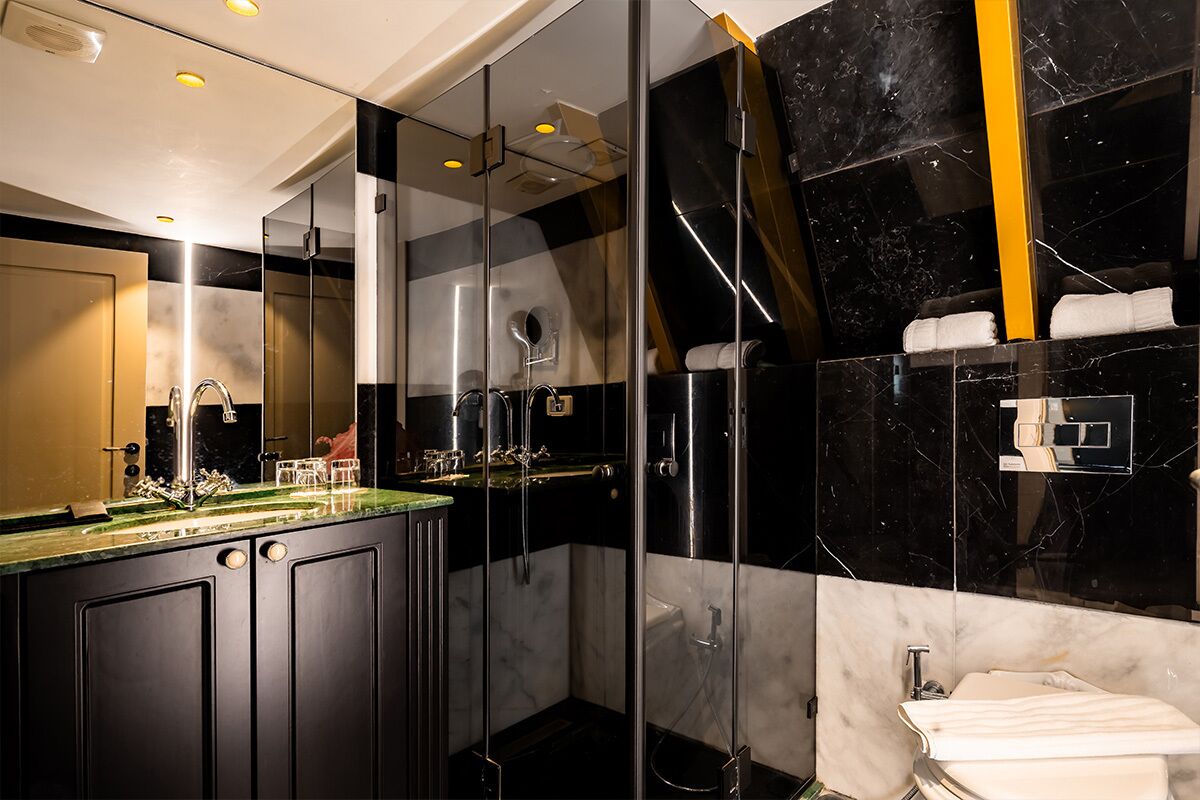 Een moderne badkamer met een douchecabine van glas, een wastafelmeubel met een marmeren blad en een apart gelegen wastafel.