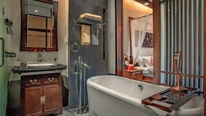 A modern bathroom with a freestanding bathtub, a vanity with a mirror, and a towel rack.