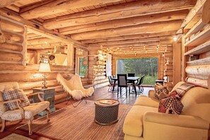En stuga byggd av timmer med en inredning som inkluderar en matplats, en soffa, en fåtölj och en lampa.
