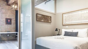 A modern bedroom with a bed, bedside table, lamp, and artwork. - Bradshaw Lofts: The Tapestry (Stratford)