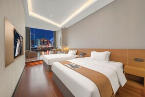 A modern hotel room with two beds, a city view, and a dining area with a table and chairs.