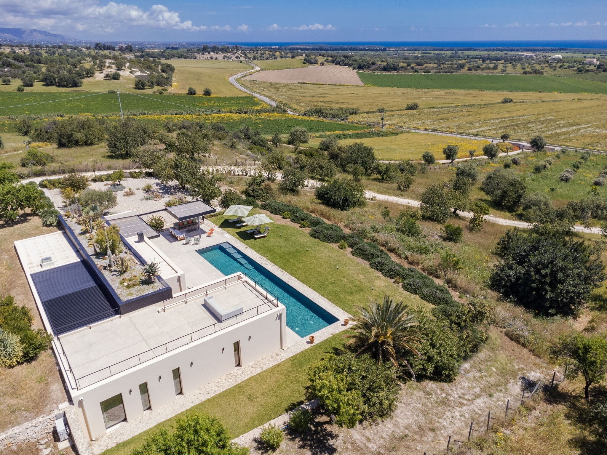 A modern house with a swimming pool, solar panels, and a view of the countryside.