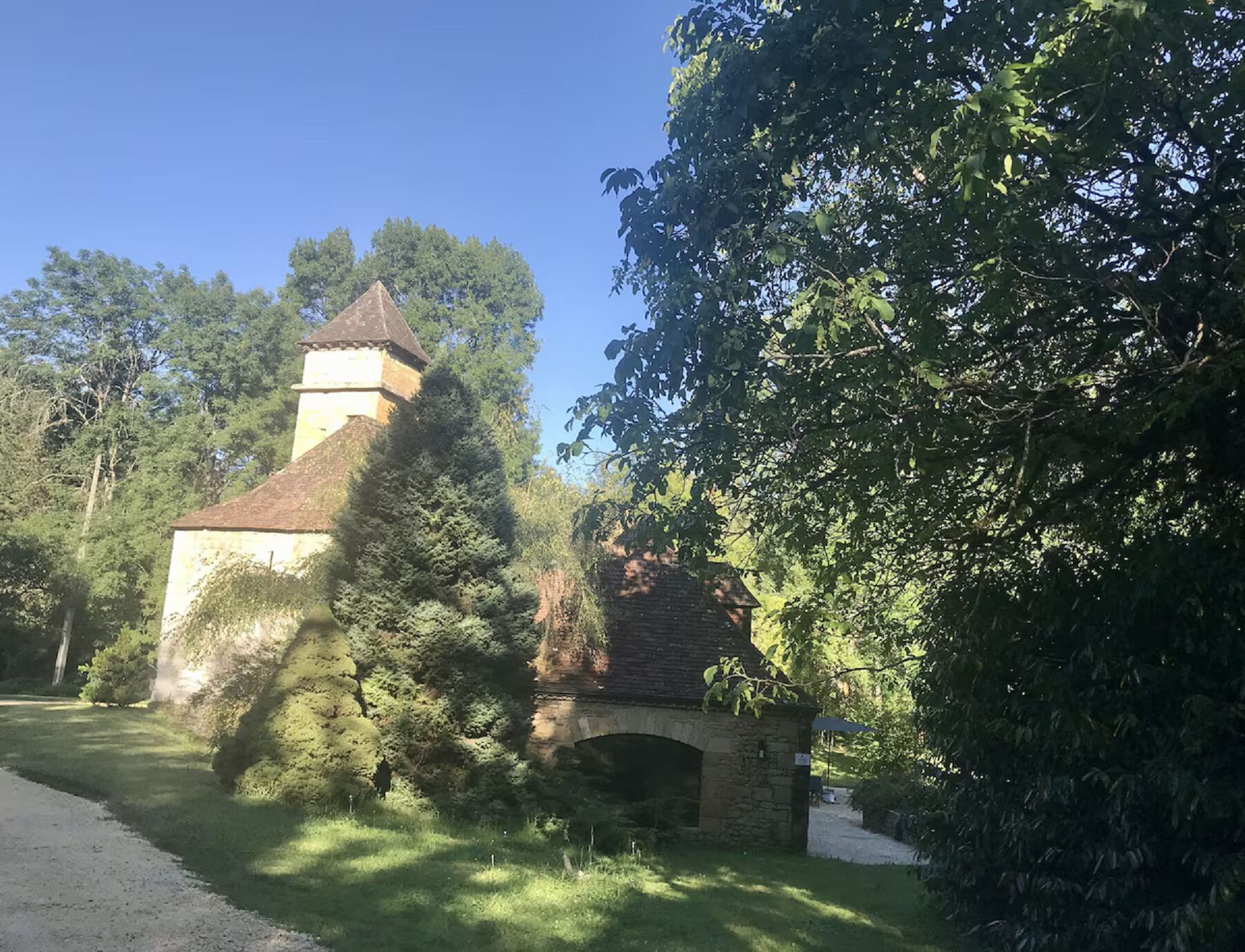 A historic building with a tower and an arched entrance, surrounded by lush greenery.