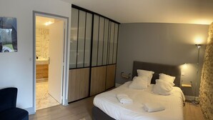 Ein Schlafzimmer mit Bett, Nachttischen, einem Kleiderschrank und einem durchgehenden Türbogen erreichbaren Badezimmer.