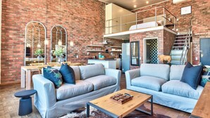 A modern living room with two sofas, a coffee table, and a kitchen area in the background. - West Side Studios Mountain View Loft (Cape Town)