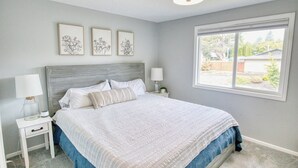 A bedroom with a bed, nightstands, wall art, and a window. - Family-Friendly 5BR Retreat – Hot Tub & Game Room (Gresham)