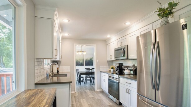 A modern kitchen with white cabinets, stainless steel appliances, and a wooden countertop. - Family-Friendly 5BR Retreat – Hot Tub & Game Room (Gresham)