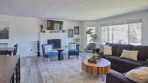 A living room with a fireplace, seating, and large windows. - Family-Friendly 5BR Retreat – Hot Tub & Game Room (Gresham)