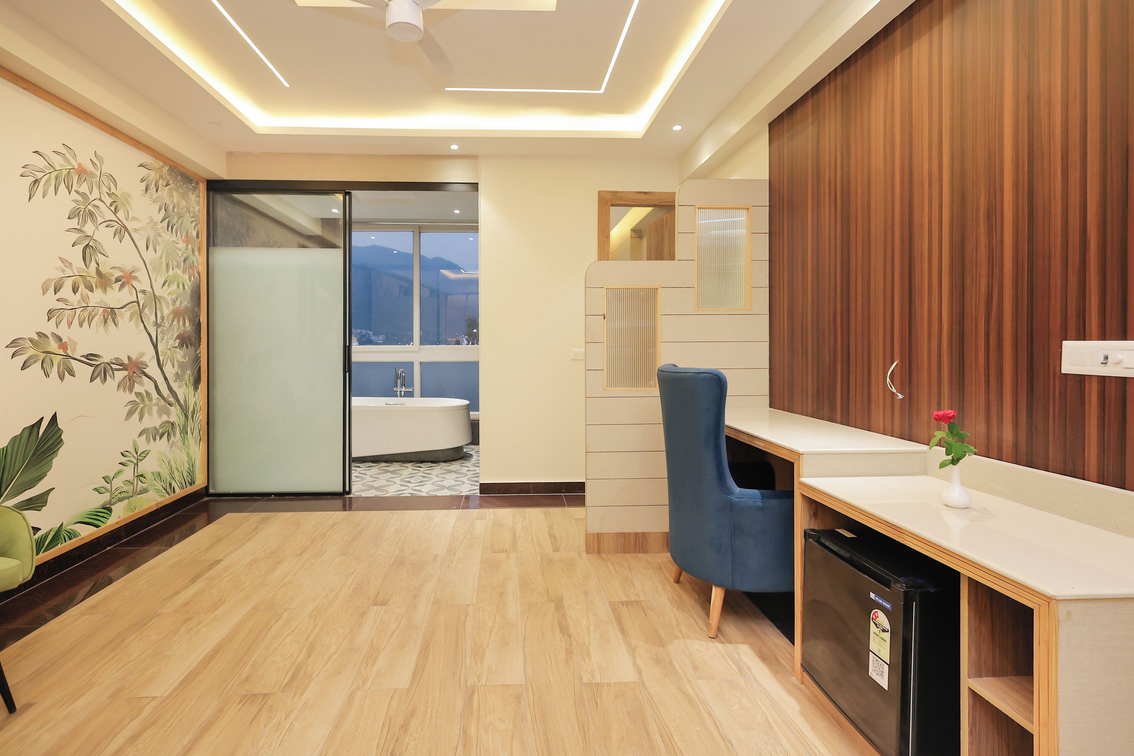 Een moderne hotel lobby met een houten vloer, een receptiebalie, een blauwe stoel en een koelkast.