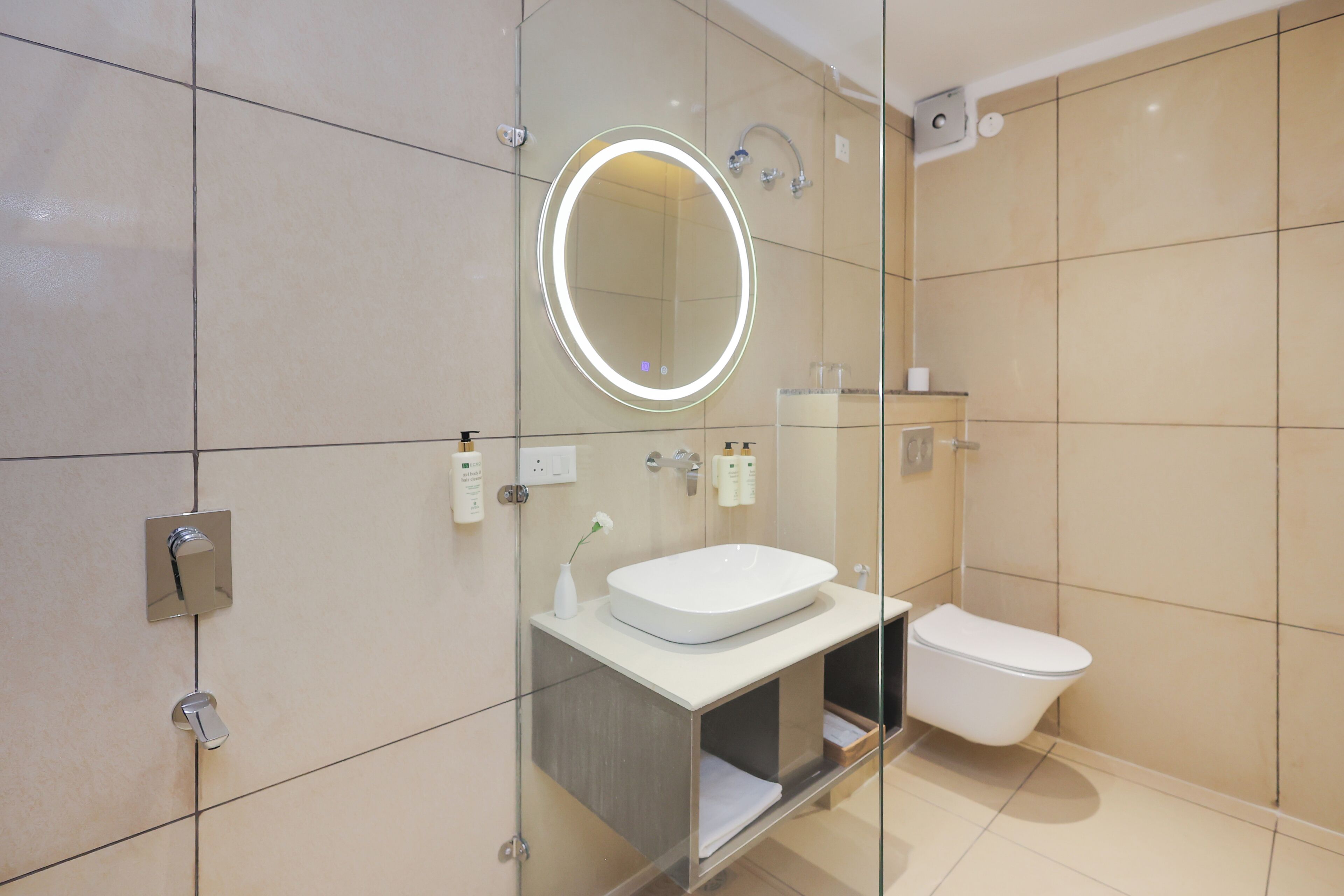 A modern bathroom with a glass-enclosed shower, a white sink, and a toilet.