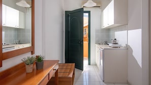 A modern kitchen with white cabinets, a wooden bench, and two potted plants.