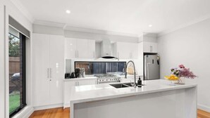 A modern kitchen with white cabinetry, a central island with a sink, and a stainless steel refrigerator.