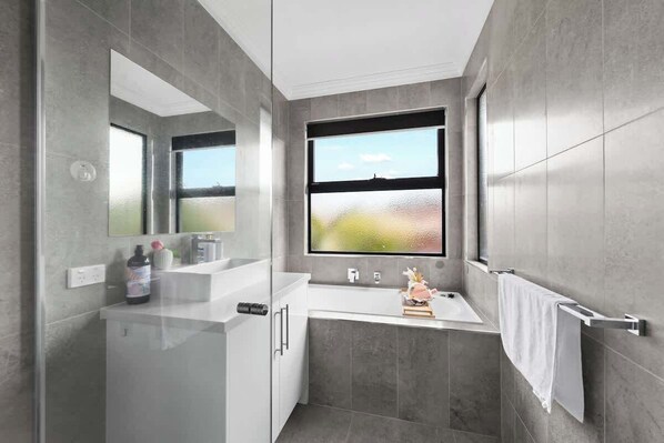 A modern bathroom with a large window, a white sink, and a mirror.