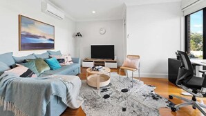 A modern living room with a sofa, a coffee table, a TV, and a chair.