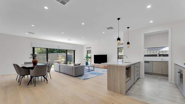 A modern living room with a dining area, a sofa, a TV, and a kitchen with a central island. - 4BR Brand new Townhouse in Ashburton Shopping Golf (Ashburton)