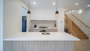 A modern kitchen with a central island, pendant lighting, and a wooden staircase. - 4BR Brand new Townhouse in Ashburton Shopping Golf (Ashburton)