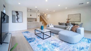 A modern living room with a sofa, coffee table, and artwork on the walls. - 4BR Brand new Townhouse in Ashburton Shopping Golf (Ashburton)