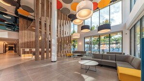 Un hall d’entrée spacieux au design moderne, comprenant un grand espace salon, un escalier et de grandes fenêtres offrant une vue sur l’extérieur.