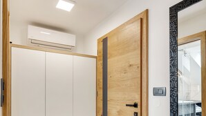 A hallway with a wooden door, white wardrobe, and a mirror.