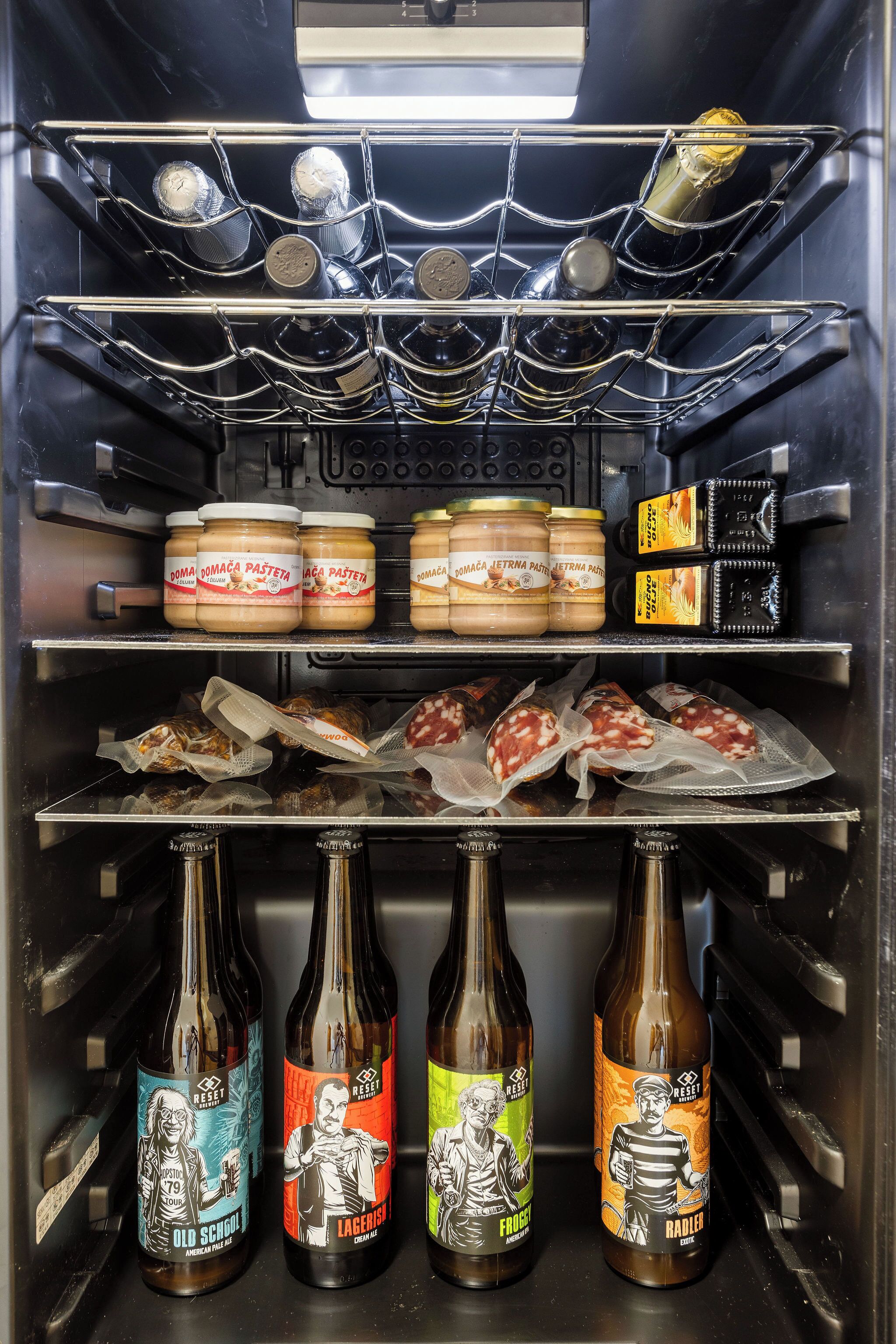Geladeira com diversos alimentos, incluindo potes de mel, garrafas de vinho e embutidos.