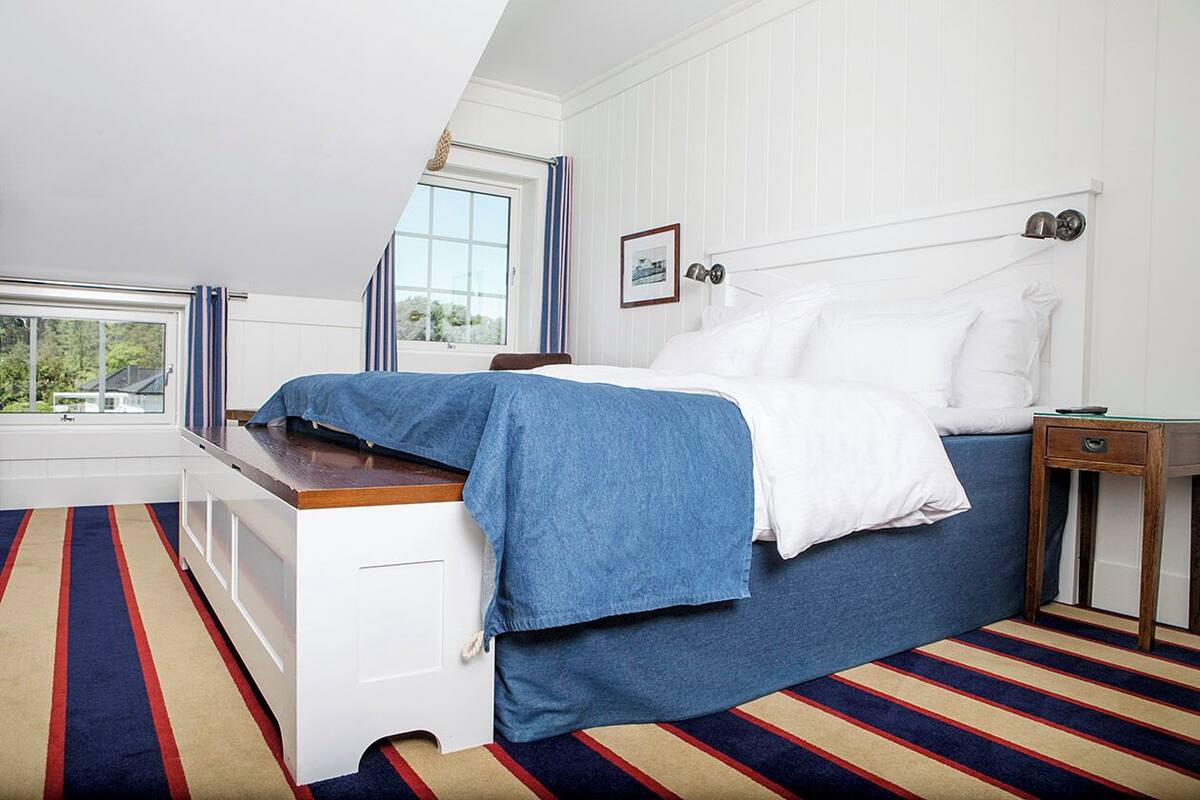 A bedroom with a bed, a nightstand, a window, and a view of the outdoors.