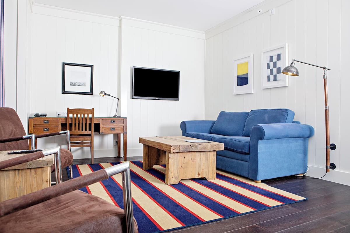 A living room with a blue sofa, wooden coffee table, and a television on the wall.