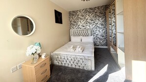 A bedroom with a bed, a dresser, a mirror, and a wall with a leaf pattern. - 1 Bed Flat - Sleeps 4 - Pets - Parking - Wifi (Grays)
