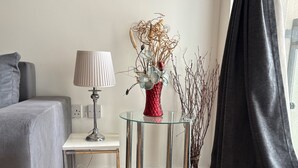 A modern living room with a grey sofa, a glass coffee table with a red vase, a lamp, and a small side table. - 1 Bed Flat - Sleeps 4 - Pets - Parking - Wifi (Grays)