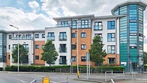 A modern multi-story residential building with a mix of brick and glass facades, balconies, and a corner tower. - 1 Bed Flat - Sleeps 4 - Pets - Parking - Wifi (Grays)