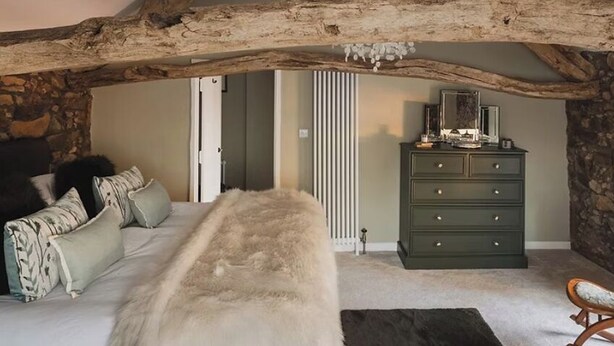 A bedroom with a large bed, a dresser, and a chair. - Boutique Luxury at The Nook (Cockermouth)