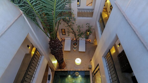 A view of a hotel atrium with a central pool, surrounded by white walls, a palm tree, and a staircase. - Architect-designed Riad close to the Secret Garden, for rent as a whole with private pool (Marrakech)