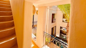 A staircase leading to a balcony with a view of a building and a palm tree. - Architect-designed Riad close to the Secret Garden, for rent as a whole with private pool (Marrakech)