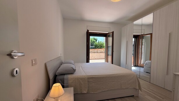 A bedroom with a bed, bedside lamp, and a view of the outside. - Oasi Perugina - maximum comfort in the beating heart of Perugia (Perugia)