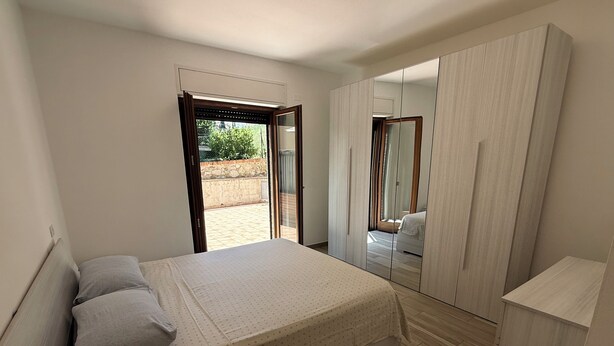 A bedroom with a bed, a wardrobe, and a sliding glass door leading to a balcony. - Oasi Perugina - maximum comfort in the beating heart of Perugia (Perugia)