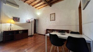 Un coin repas avec une table en bois et des chaises noires, un mur blanc orné de tableaux encadrés et un plafond en bois.