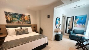 Une chambre d’hôtel moderne avec un grand lit, un petit coin salon et des œuvres d’art accrochées aux murs.