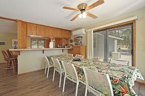 A kitchen with wooden cabinets, a dining table with chairs, and a ceiling fan.