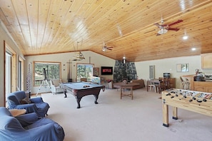 A spacious living room with a pool table, foosball table, and a stone fireplace.