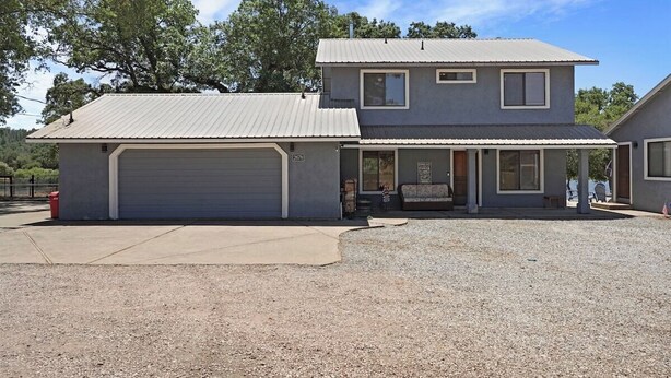 Une maison à deux étages avec un garage, une véranda et une allée gravillonnée.