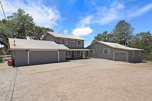A two-story house with a garage, a covered driveway, and a gravel front yard.