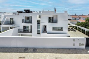 Ein modernes, mehrgeschossiges Gebäude mit Balkonen, großen Fenstern und einem flachen Dach mit Solarpanels.