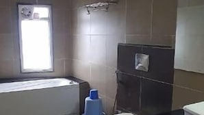 A small, dimly lit bathroom with a toilet, a sink, and a window. - Hotel Shree Vilas (Nathdwara)